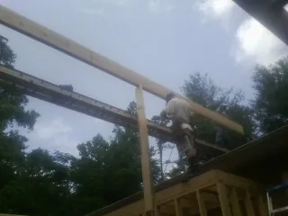 Carpenter setting a ridge beam over a new addition frame — Ice Dam Removal by Roofing Brothers in Sandpoint