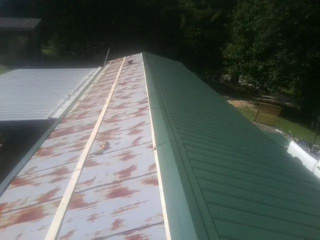 Old rusted panels beside newly installed green metal roofing — Wind Damage Roof Repair by Roofing Brothers in Sandpoint
