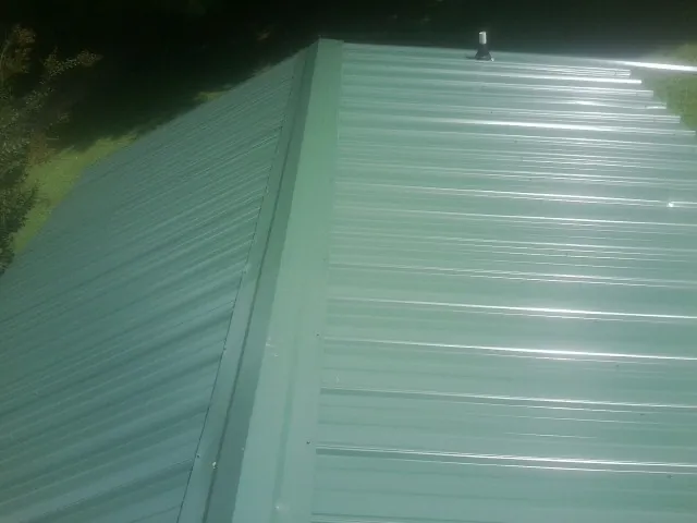 New green metal panels meeting at the ridge of a roof — Flat Roof Repair work by our crew in Sandpoint