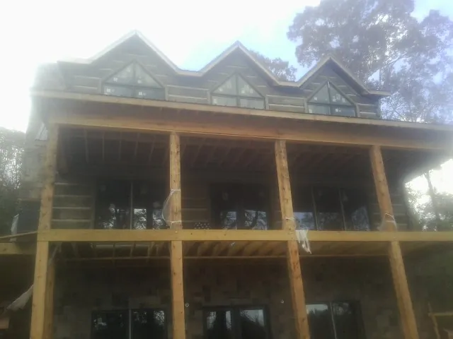 Dormers and porch framing on a large log home under construction — Roof Coating work by our crew in Sandpoint