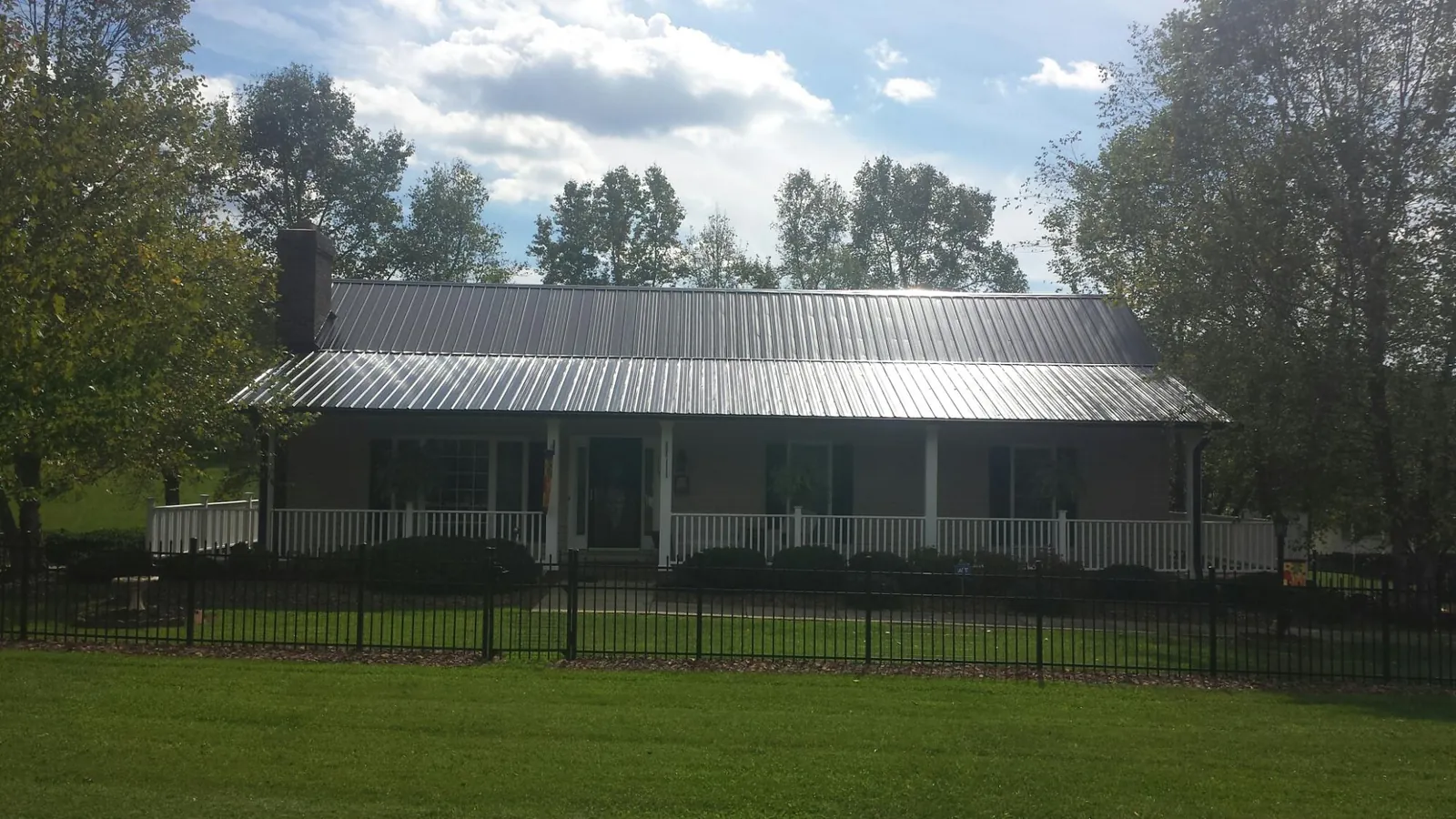 Gray metal roof on a brick ranch with a full width front porch — Gutter Guard Installation work by our crew in Sandpoint