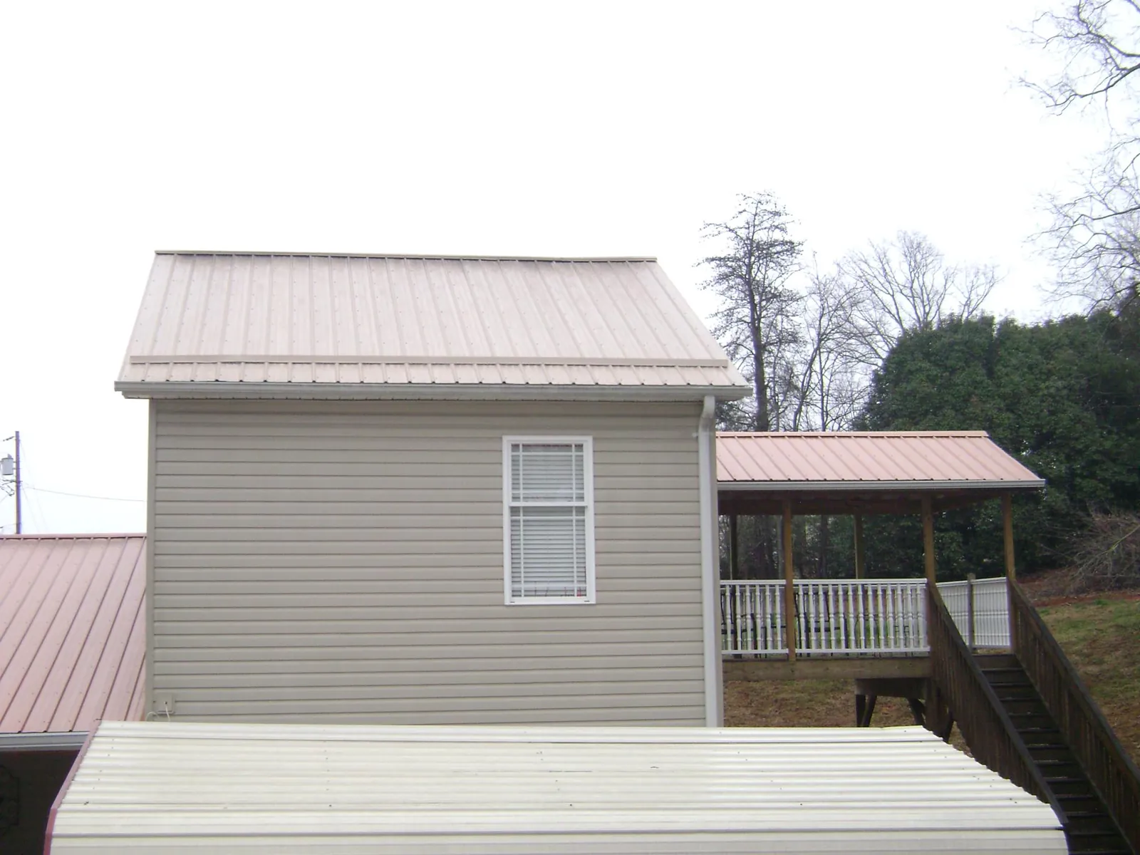 Tan metal roofs on a two story addition and attached porch, from a Roof Replacement job in Sandpoint